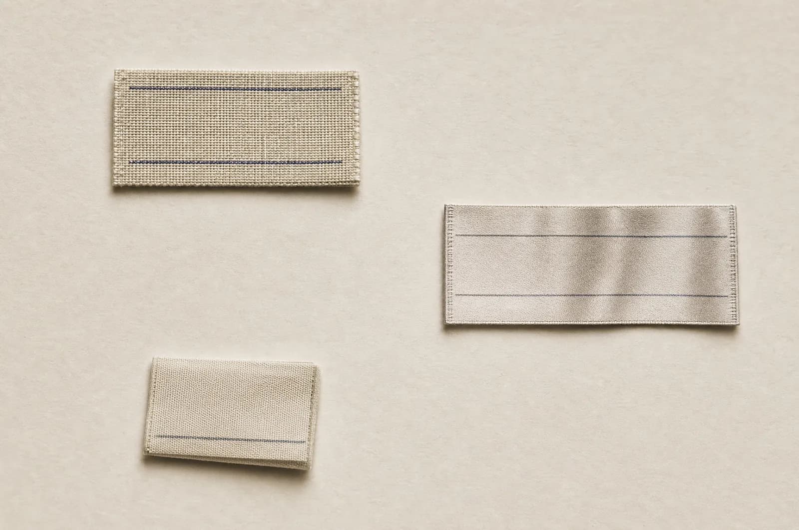 Three blank garment labels laid out separately on pale paper